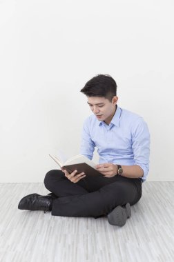 Takım elbiseli bir kitap okuma ve gülümseyen katta oturan genç adam