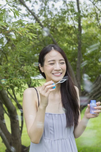 シャボン玉を吹くを笑顔若いアジア女性 — ストック写真