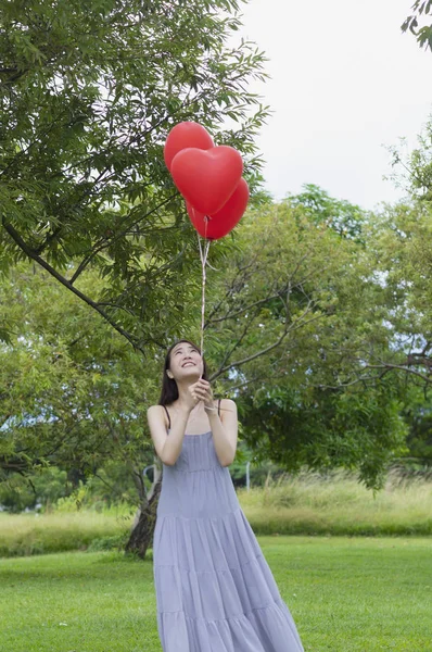 年轻的亚洲女人拿着气球 面带微笑地看着它 — 图库照片