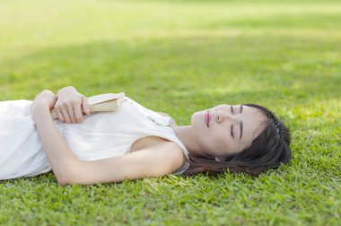 Kestiriyor çim üzerinde yalan beyaz bir elbise giyen genç Asyalı kadın