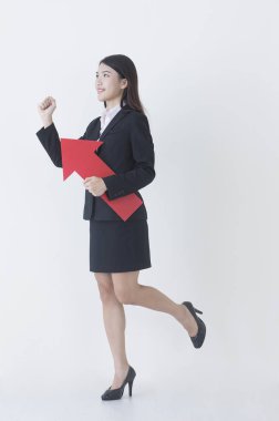 Bir ok tutarak ve uzağa arıyorsunuz gülümseyen bir takım elbise giymiş genç Asyalı kadın