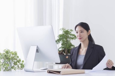 Masada oturan ve onun bilgisayarı kullanan Genç Asyalı kadın