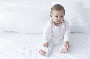 Yatakta oturmuş ve uzağa arıyorsunuz küçük Asya bebek