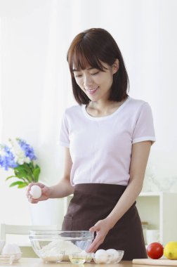 Yumurta pişirme ve gülümseyen Genç Asyalı kadın