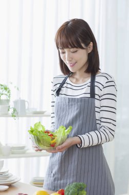 Bir kase ve salata tutarak ve gülümseyen Genç Asyalı kadın
