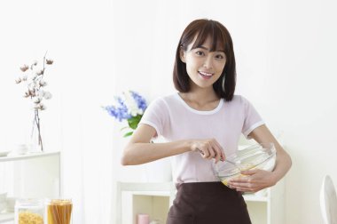 Yumurta pişirme ve kameraya gülümseyen Genç Asyalı kadın