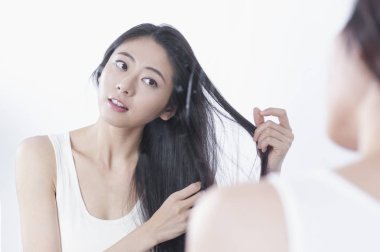 Siyah uzun saçlı Genç Asyalı kadın saçları ve aynaya bakarak eller