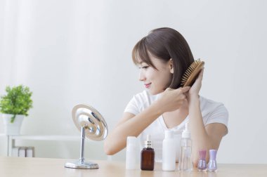 Onun saç tarama gülümseyen Genç Asyalı kadın