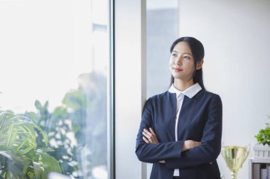 Genç Asyalı kadın çapraz ve gülümseyerek uzakta seyir silah