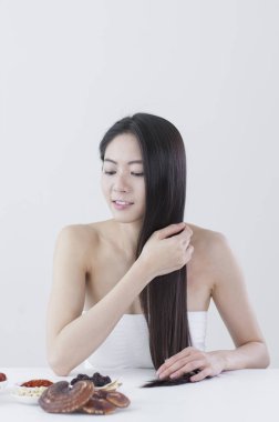 Güzel Asyalı kadın saçını tutan ve uzağa bakarak eller