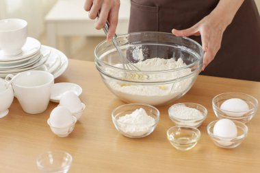 Genç Asyalı kadın mutfakta kase un koyarak