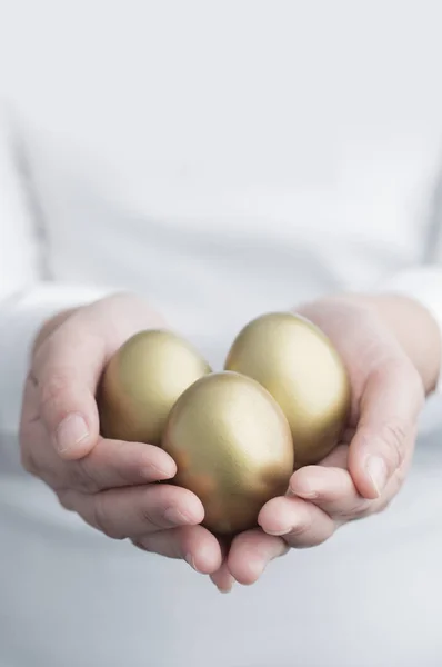Golden Eggs in hands on background,close up