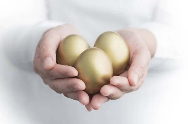 Golden Eggs in hands on background,close up