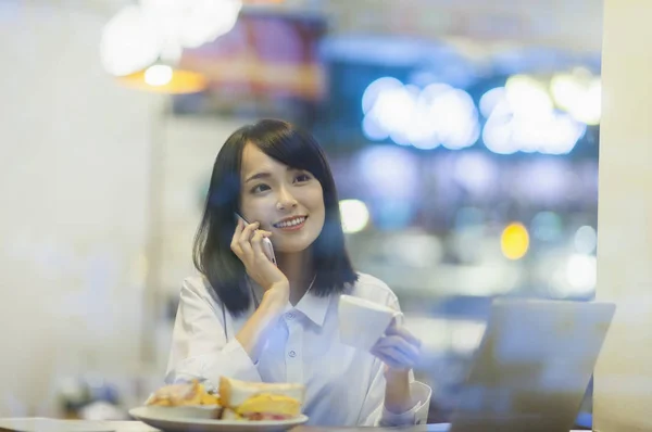 Young Asian woman wearing a suit smiling talking on the phone