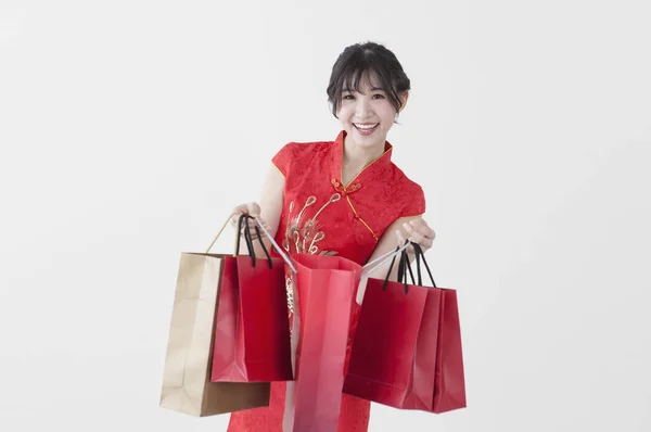 Young Chinese woman wearing a cheongsam holding some gifts and smiling at the camera