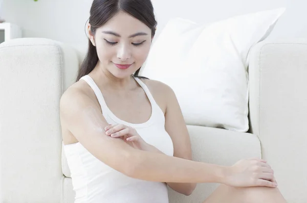 Young Asian woman putting lotion on her hand