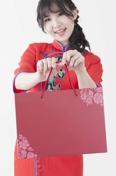 穿着旗袍 拿着礼物对着镜头微笑的年轻中国女子 — 图库照片