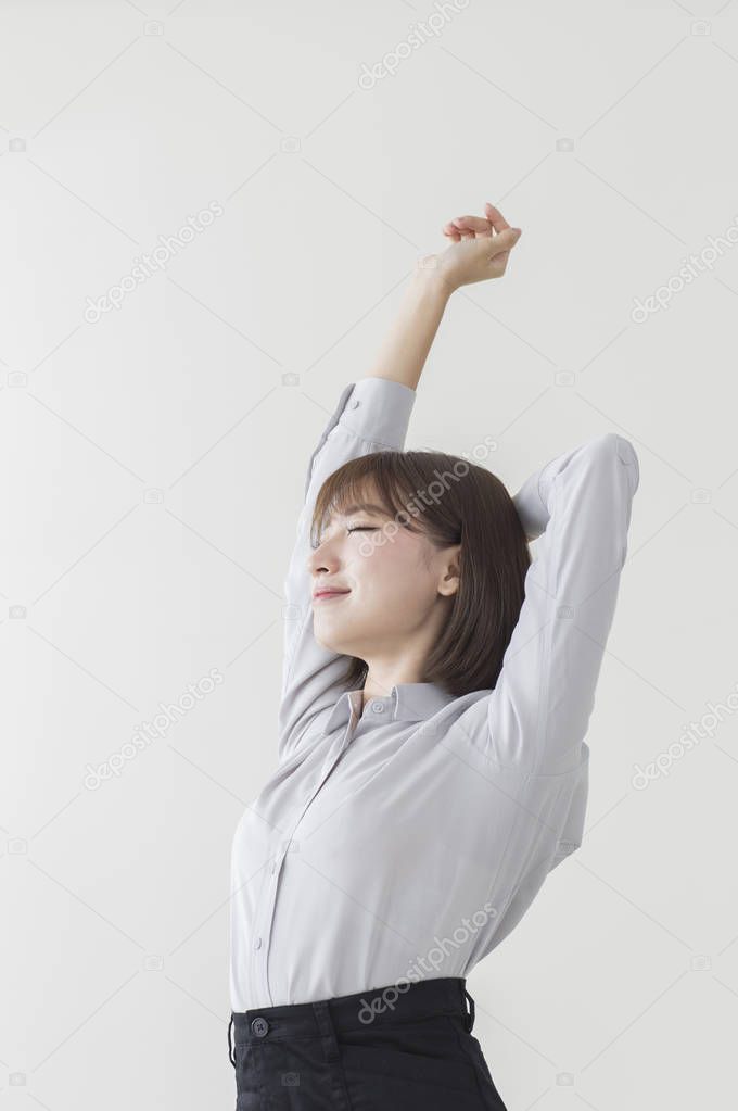 Young Asian woman wearing a suit hands up and stretching her body