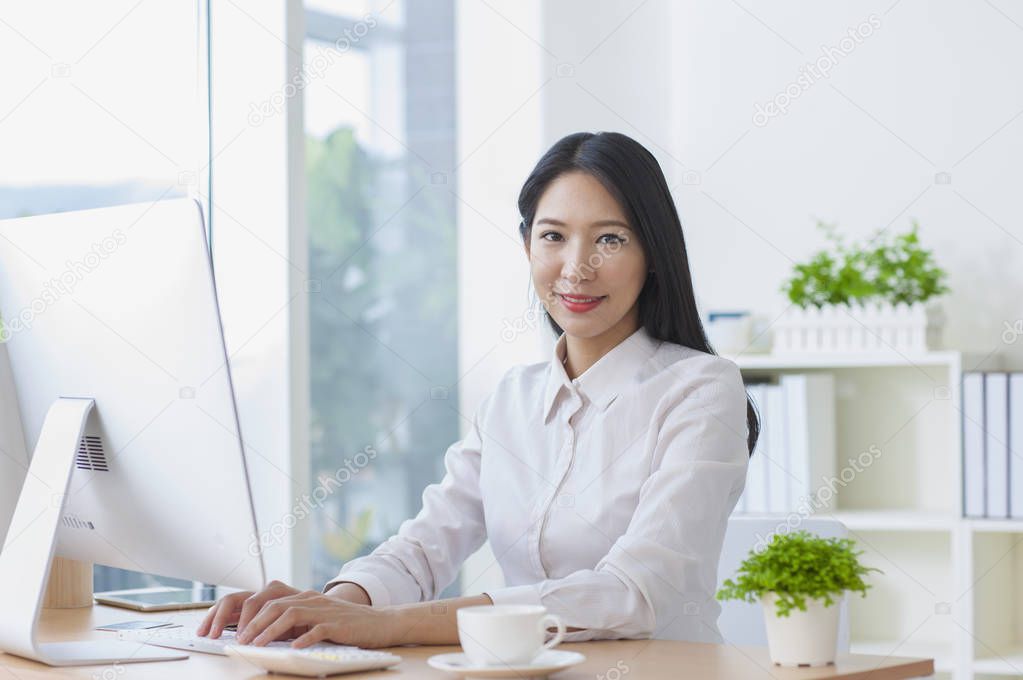 Young Asian woman using the computer and smiling at the camera