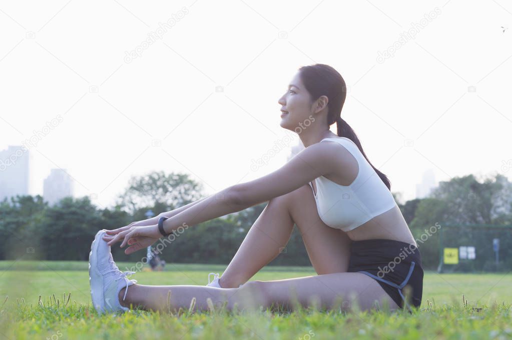 Young Asian woman stretching her legs in the park