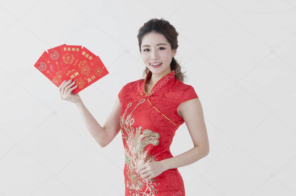 Young Chinese woman wearing a cheongsam holding some red envelopes and smiling at the camera
