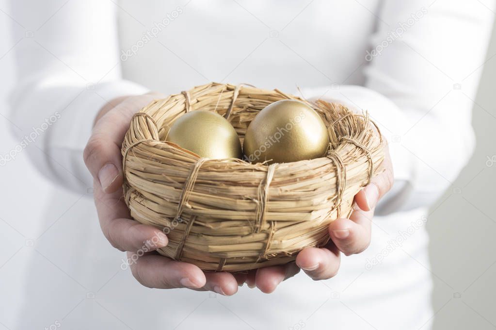  Golden Eggs in hands on background,close up