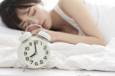 Asyalı kadın kadın uyuyor. Çalar saat odak