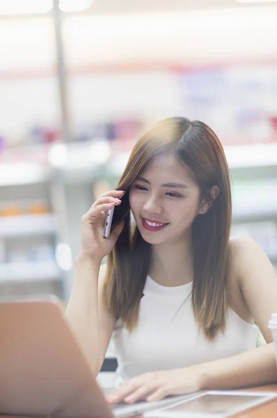 Jovem Mulher Asiática Sorrindo Falando Telefone Olhando Para Seu Laptop — Fotografia de Stock