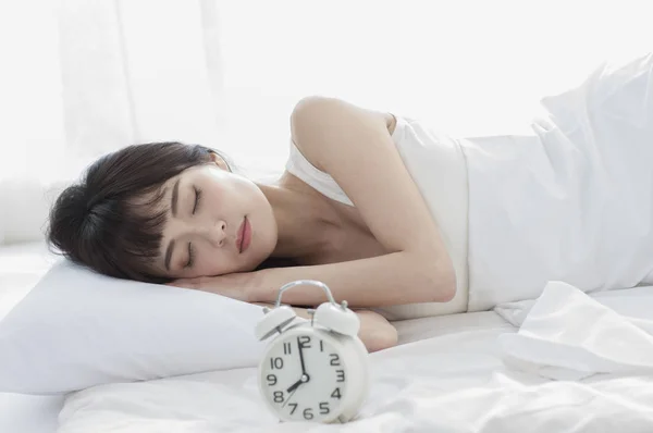 アジア女性が眠っています フォーカスの目覚まし時計 — ストック写真