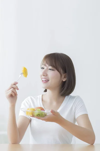 Bir Tabak Meyve Yeme Gülümseyen Genç Asyalı Kadın — Stok fotoğraf