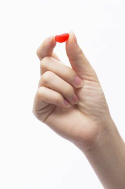 hand holding a red pill isolated on white background