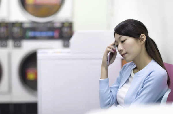 portrait of  asian woman with phone, washing clothes