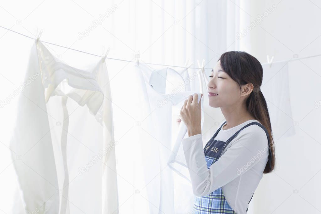 portrait of  asian woman  putting  laundry on a rope 