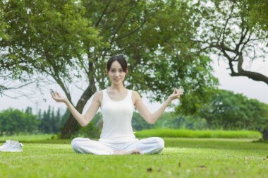 Güzel genç asyalı kadın parkta meditasyon yapıyor