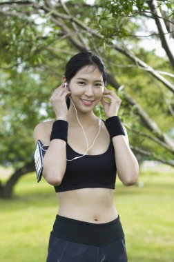 Güzel genç asyalı kadın parkta kulaklık spor yapıyor
