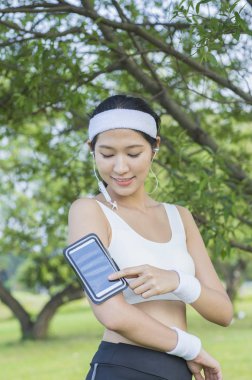 Güzel genç asyalı kadın parkta kulaklık spor yapıyor