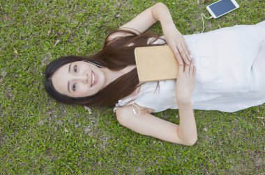 Yaz parkında telefon ve kitap ile güzel asyalı kadın