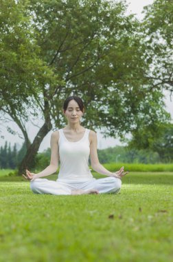 Güzel genç asyalı kadın parkta meditasyon yapıyor