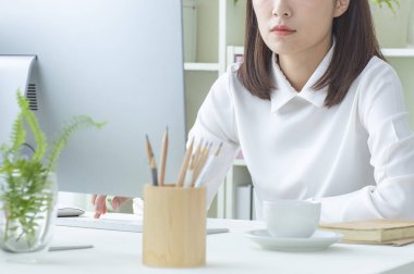 Dizüstü bilgisayarda ofiste çalışan Asyalı iş kadını