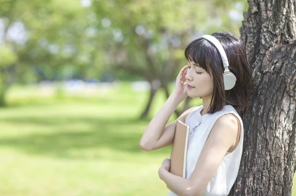 年轻的亚洲女人在耳机在夏天公园 — 图库照片