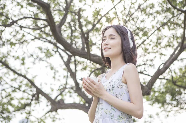 年轻的亚洲女人在耳机在夏天公园 — 图库照片