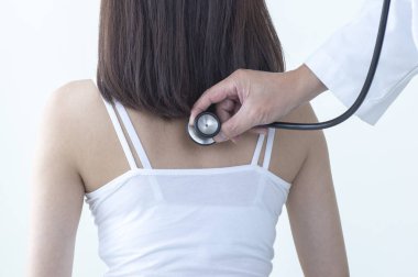 Steteskoplu bir doktor kadın hastayı muayene ediyor.