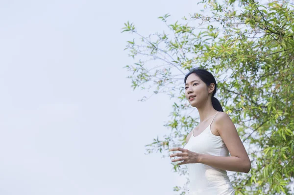 夏の公園で水を持つ若いアジアの女性 — ストック写真