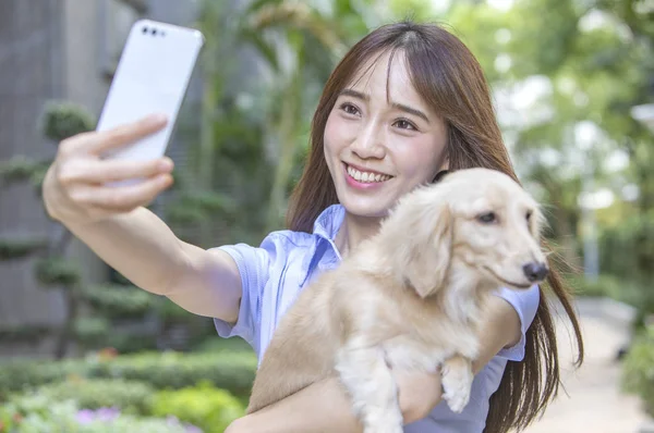 路上で自分撮りをする犬を持つ若いアジアの女性 — ストック写真