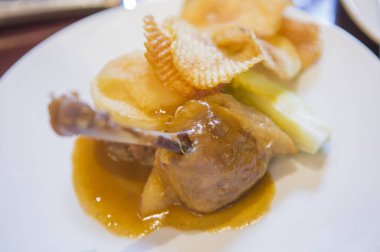 Yakın plan kızarmış patates ve beyaz tabakta ördek bacağı.