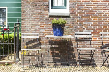 Tuğla duvarlı pencere ve dışarıda sandalyeli ahşap masa.