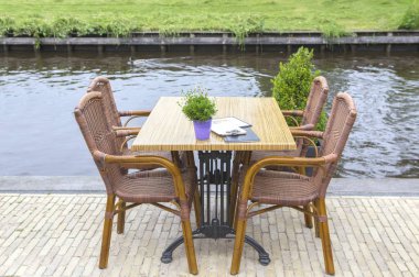 Kanal yakınındaki terasta masa ve sandalyeler. 