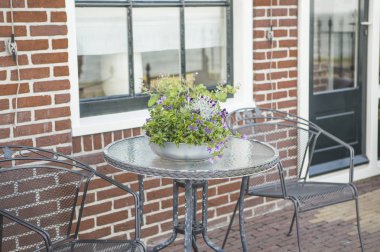 Teras kafe masası ve masasında güzel çiçekler olan sandalyeler. 