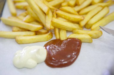 Beyaz arka planda patates kızartması ve ketçap.
