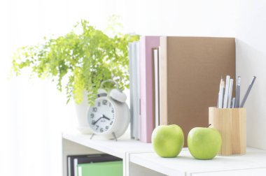 Modern, parlak bir iç mekan, rafta saat ve kitaplar var.